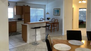 A kitchen with a dining area, wooden cabinets, a sink, and a window with blinds.