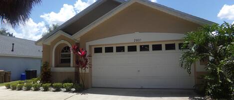 A residential house with a beige exterior, a white garage door, and a number 2807 on the roof.