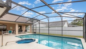A covered swimming pool with a metal roof, surrounded by a patio area with chairs and a table. - Orange Tree Pool Home with spa. Enjoy recreation and relaxation in this inviting community near the best of Orlando's hot spots! (Clermont)