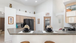 A modern kitchen with a central island, wooden cabinets, stainless steel appliances, and a decorative sign on the wall. - Orange Tree Pool Home with spa. Enjoy recreation and relaxation in this inviting community near the best of Orlando's hot spots! (Clermont)