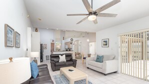A modern living room with a brown leather sofa, a white sofa, and a wooden coffee table. There is a ceiling fan, a lamp, and a rug. - Orange Tree Pool Home with spa. Enjoy recreation and relaxation in this inviting community near the best of Orlando's hot spots! (Clermont)