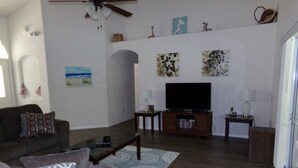 A living room with a sofa, coffee table, TV, and decorative items on the wall. - Orange Tree pool home features elegance, comfort, space and prime location! Book now! (Clermont)
