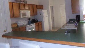 A compact kitchen with wooden cabinets, a microwave, a toaster, and a refrigerator. - Orange Tree pool home features elegance, comfort, space and prime location! Book now! (Clermont)