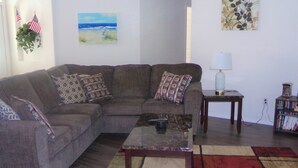 A living room with a sectional sofa, a coffee table, a rug, and a bookshelf. - Orange Tree pool home features elegance, comfort, space and prime location! Book now! (Clermont)