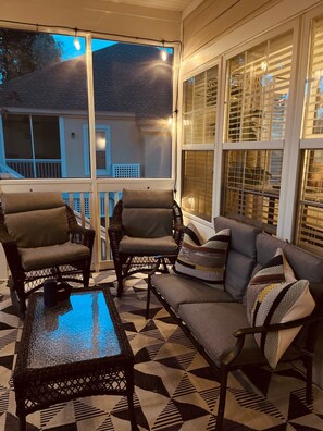 Relax in this inviting outdoor seating area with a coffee table, two chairs, and a sofa, surrounded by a window with a view.