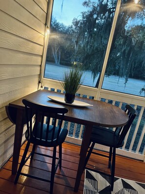 Enjoy a tranquil outdoor space with a round table and four chairs, surrounded by a railing and a beautiful view of the water and trees.