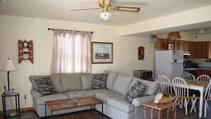 A living room with a sofa, coffee table, and dining area with chairs and a table. - Pony Swim Ridge- Waterviews, Close to Memorial Park (Chincoteague)