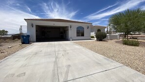 A single-story building with a garage, a small garden, and a clear sky. - Spacious, Clean, Family Friendly, Lake Havasu Home with Boat Deep Garage! (Lake Havasu City)