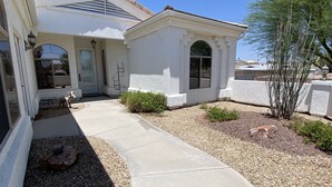 A house with a concrete driveway, a small garden with rocks and plants, and a metal fence. - Spacious, Clean, Family Friendly, Lake Havasu Home with Boat Deep Garage! (Lake Havasu City)