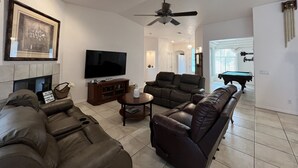 A living room with a flat-screen TV, leather sofas, a coffee table, and a fireplace. - Spacious, Clean, Family Friendly, Lake Havasu Home with Boat Deep Garage! (Lake Havasu City)