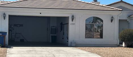 Una casa de un piso con garaje, un ventanal arqueado grande y el número 2257 en la pared.