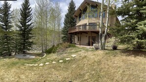 Una casa a due piani con un balcone, circondata da alberi e un vialetto in pietra.