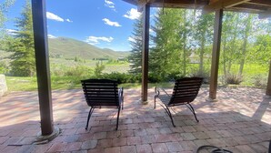 Una veranda riparata con due sedie di legno rivolte verso una vista panoramica su colline e alberi.