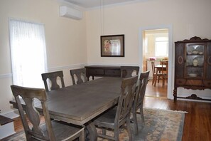 A dining room with a wooden table and chairs, a framed picture on the wall, and a cabinet with dishes.