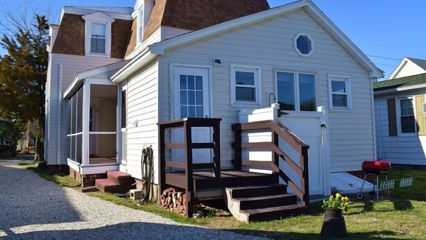 A two-story house with a front porch, a garage, and a small front yard. - Sage House-Historic Downtown Location (Chincoteague)