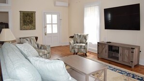 A living room with a sofa, armchairs, a coffee table, a TV, and a cabinet. - Sage House-Historic Downtown Location (Chincoteague)