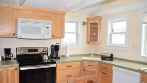 A kitchen with wooden cabinets, a black stove, a microwave, a coffee maker, and a dishwasher. - Sage House-Historic Downtown Location (Chincoteague)