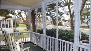 A porch with white railings and rocking chairs. - Sage House-Historic Downtown Location (Chincoteague)