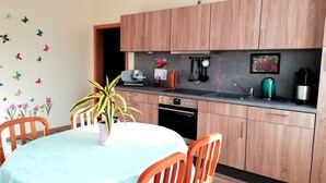 A modern kitchen with wooden cabinets, a built-in oven, a sink, and a coffee maker.