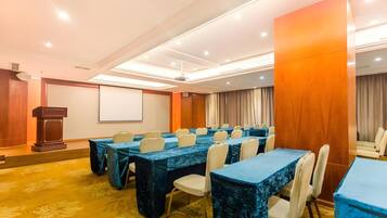 A conference room with multiple tables and chairs, a podium, and a projection screen.
