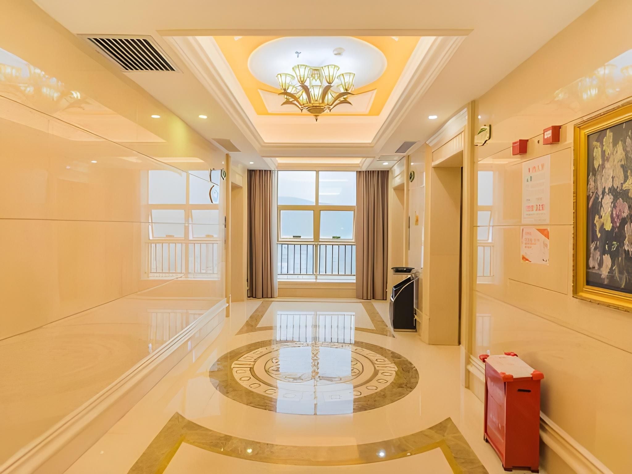 A hotel lobby with a chandelier, large windows, and a polished floor.