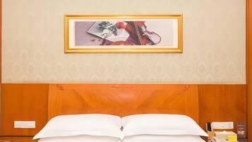 A hotel room with a large bed, a nightstand, a framed picture on the wall, and a wooden headboard.