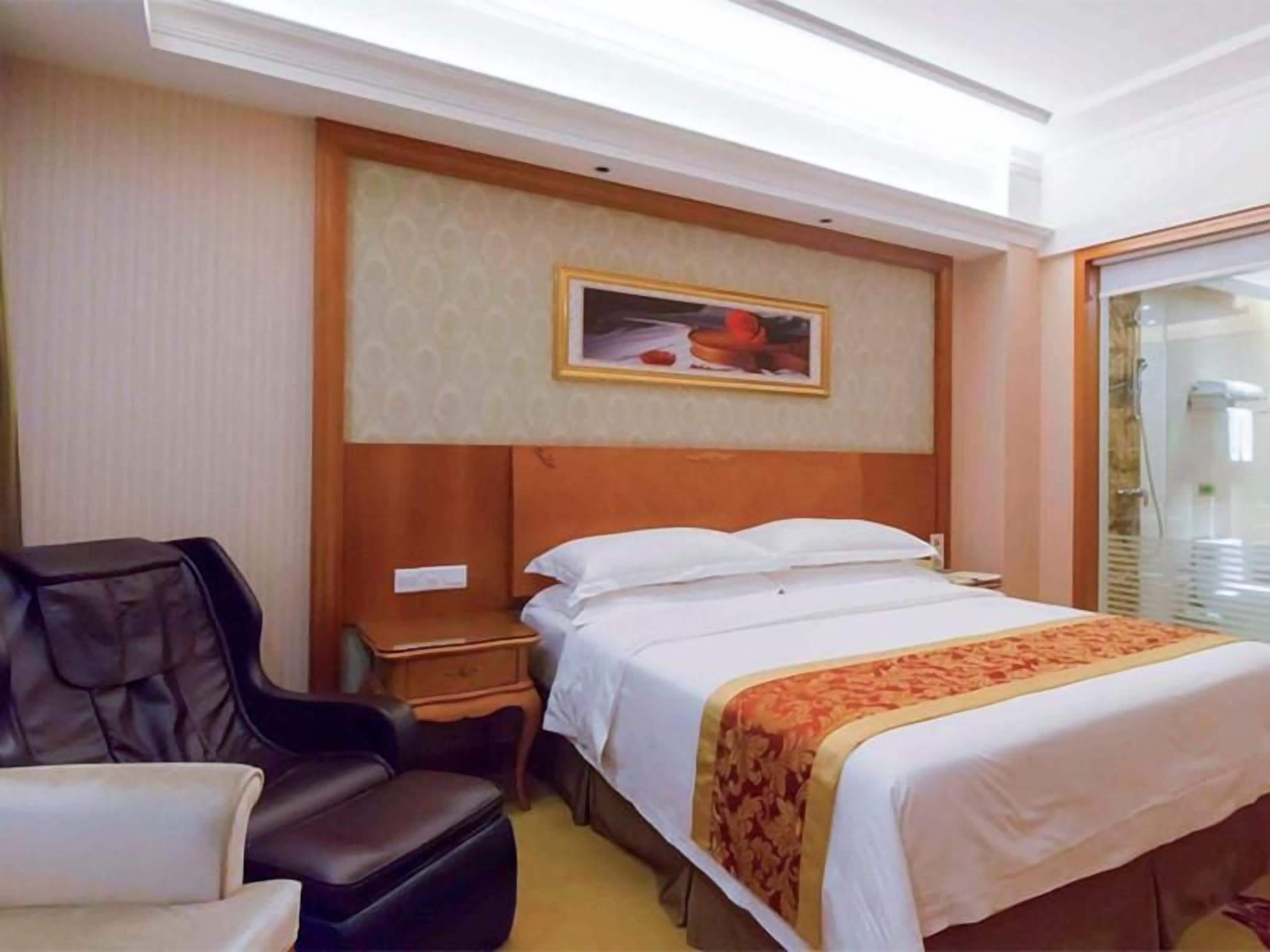 Una habitación de hotel con una cama, un escritorio, una silla y una ventana.