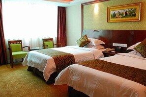 Une chambre d’hôtel avec deux lits, un bureau, une chaise et un tableau au mur.