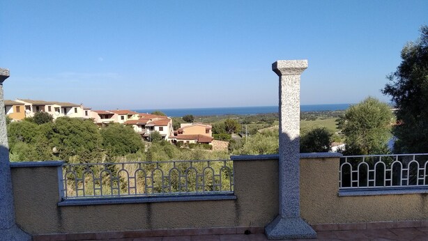 Una terrazza con pavimento piastrellato, ringhiera in metallo e colonne in pietra.