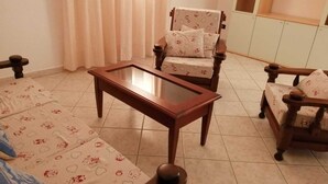 Un soggiorno con un tavolino da caffè in vetro, due poltrone con cuscini decorati e un divano con lo stesso design.