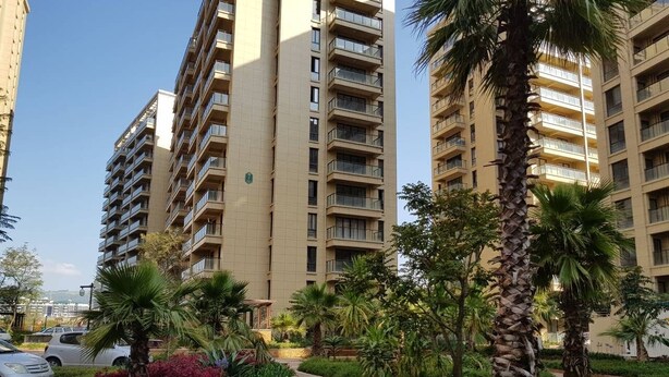 Un edificio residenziale con diversi balconi, circondato da verde curato e un vialetto lastricato.