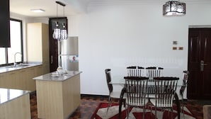 Una cucina moderna con isola centrale, zona pranzo con tavolo e sedie in vetro e un tappeto decorato.