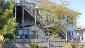 Ein zweistöckiges Haus mit einer Holzterrasse und einer Treppe, die zum oberen Stock führt.