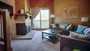 Un salon chaleureux avec une cheminée, un canapé, une table basse et une carte du monde accrochée au mur.