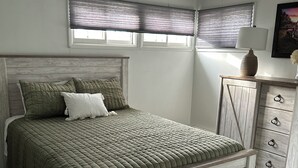 A bedroom with a wooden bed, a nightstand, a lamp, and a window with blinds. - West Avenue Place, quiet neighborhood, close to downtown  (Cody)