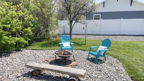 An outdoor seating area with two blue Adirondack chairs, a fire pit, and a wooden bench. - West Avenue Place, quiet neighborhood, close to downtown  (Cody)
