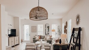 A spacious living area with a dining table, sofas, and a television. - Martinique! Luxury! Beach House on the Crescent with Golf Cart.  (Gulf Shores)