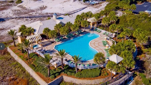 An aerial view of a resort with a central swimming pool, surrounded by palm trees and lounge areas. - Martinique! Luxury! Beach House on the Crescent with Golf Cart.  (Gulf Shores)