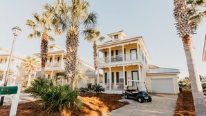 A two-story house with a balcony, a garage, and a golf cart parked in front. - Martinique! Luxury! Beach House on the Crescent with Golf Cart.  (Gulf Shores)