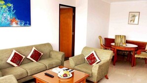 A living room with two sofas, a coffee table, and a dining area with a table and chairs. - Asana Kawanua Jakarta (Jakarta)