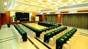 A conference room with a long table, white chairs, and a stage with a screen. - Asana Kawanua Jakarta (Jakarta)