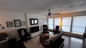 A living room with a fireplace, a ceiling fan, and large windows. - Cozy 3-Bdrm  Escape w/ Yard - Budget-Friendly (Austin)