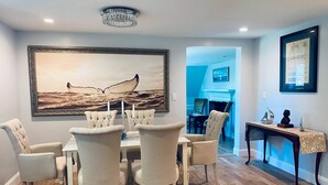 A dining area with a large ocean-themed painting, a chandelier, and a table set for four. - Charming, newly renovated house, a few steps from bike path. (Dennis Port)