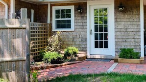 A house with a wooden exterior, a front door with a glass panel, and a small porch area. - Charming, newly renovated house, a few steps from bike path. (Dennis Port)