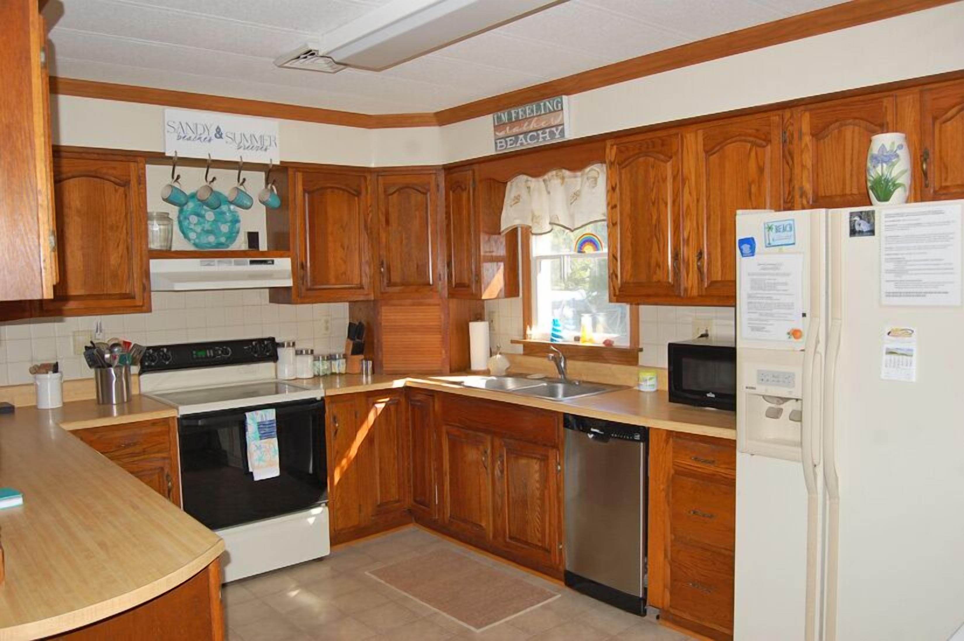 A kitchen with wooden cabinets, a stove, a dishwasher, and a refrigerator.