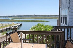 Une terrasse en bois offrant une vue sur une étendue d’eau calme et une côte lointaine.