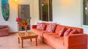 Una sala de estar con un sofá, una mesa de madera con un florero y una decoración de tabla de surf en la pared.