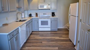 Une cuisine de taille réduite, dotée de meubles blancs, d’un four à micro-ondes, d’une cuisinière et d’un réfrigérateur.