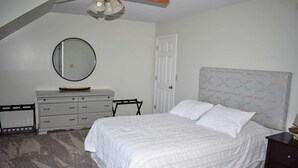 Une chambre à coucher avec un lit, une commode, un miroir et une porte.