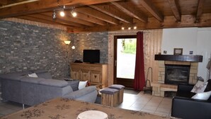 A cozy living room with a stone wall, a fireplace, a television, and a sofa. - WARM ALTITUDE BARN, Cambasque, 8 people (Cauterets)